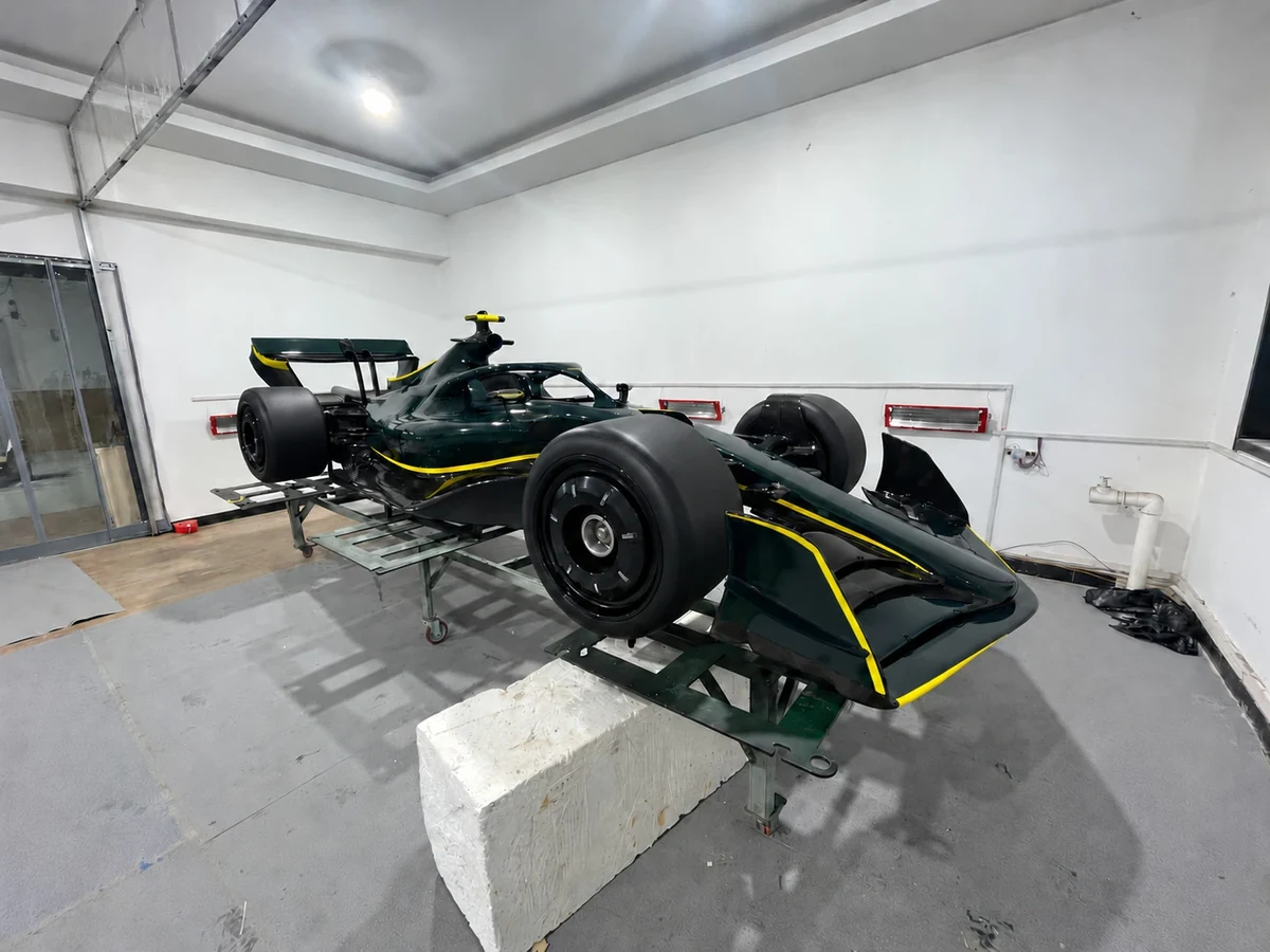 Formula-style show car in dark green with yellow accents, front three-quarter view, graphics removed