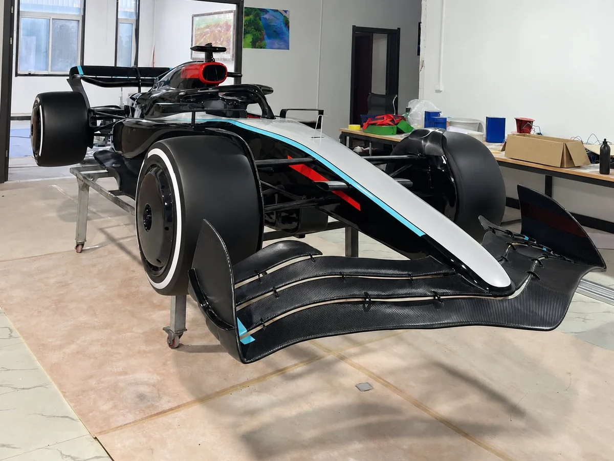 Formula-style show car in black and silver with turquoise accents, front view, graphics removed